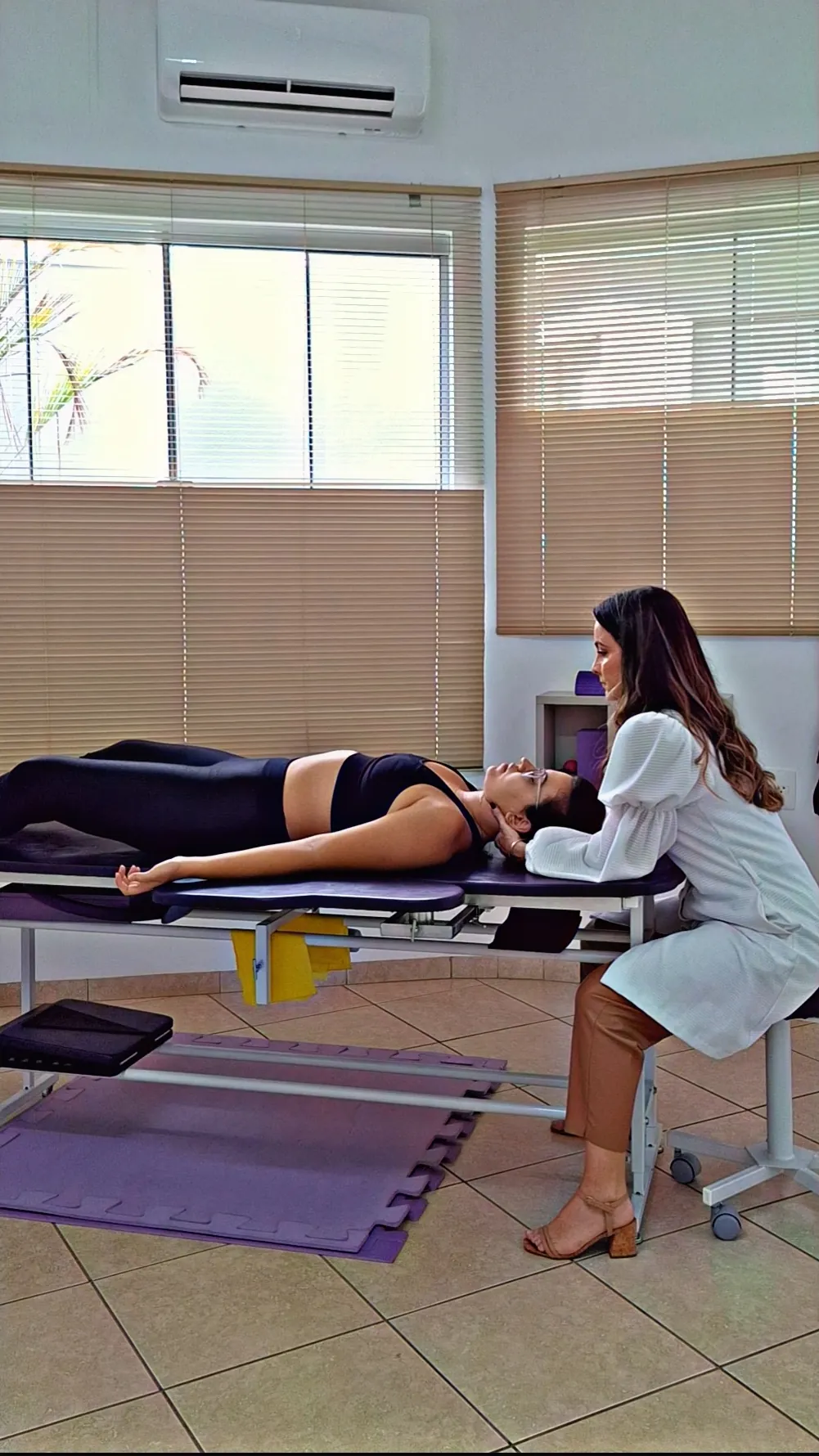 Dra. Gisela fazendo terapia manual no pescoço de uma paciente deitada na maca