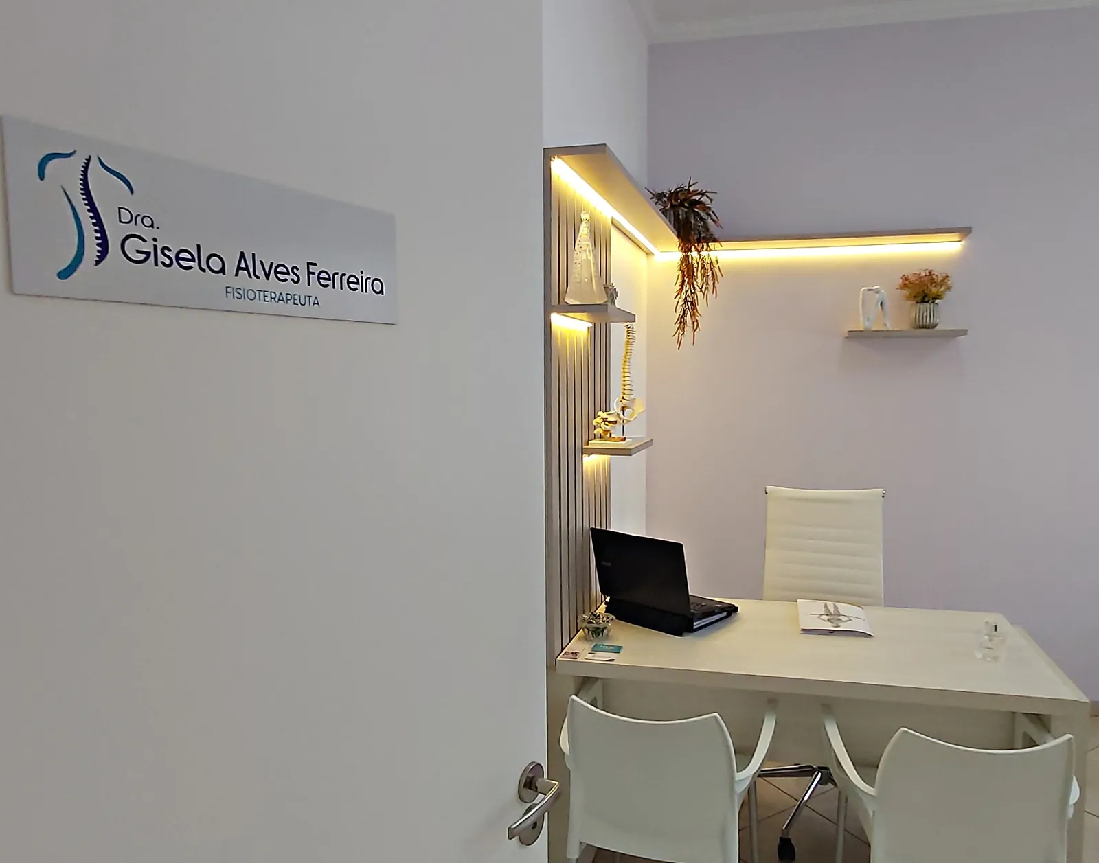 Entrada do consultório, com a placa da Dra. Gisela Alves Ferreira, fisioterapeuta, e a mesa de atendimento iluminada por LED