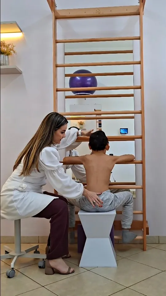 Dra. Gisela avaliando as costas de uma criança sentada diante do espaldar
